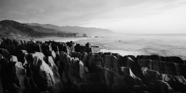 Free photo panaroma of pancake rocks in the scenic view of mountains, beach and sunset.