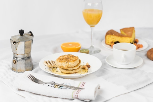 팬케이크; 과일; 주스; 아침 식사 테이블에 케이크 조각과 커피 컵