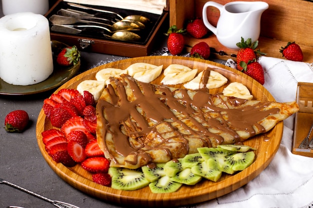 Pancake poured with liquid chocolate with fruit