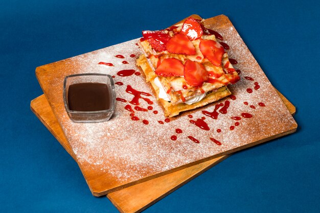 Pancake with cream and strawberry on wooden board