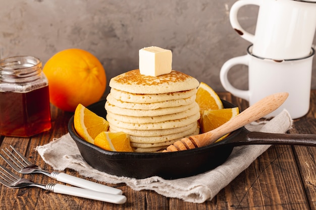 Pancakes in pan with dipper and honey jar