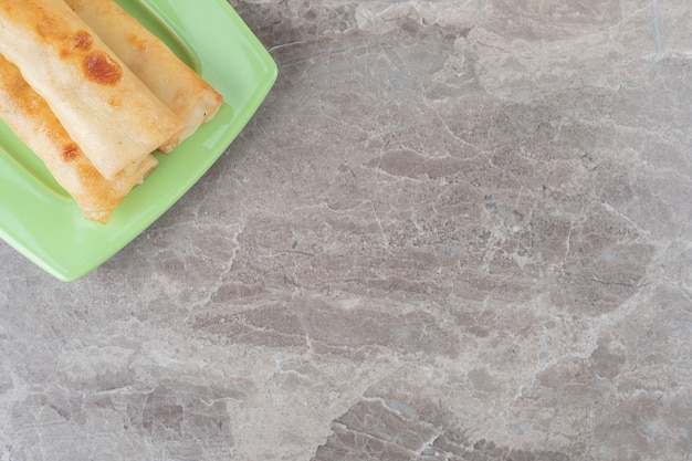 Free photo pancakes stacked on a green platter on marble surface