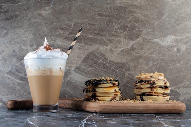 Pancakes with banana and chocolate topping on wooden board with delicious coffee. 