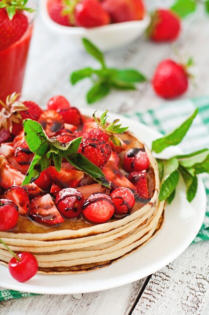 Pancakes with berries and strawberry smoothie in a rustic style
