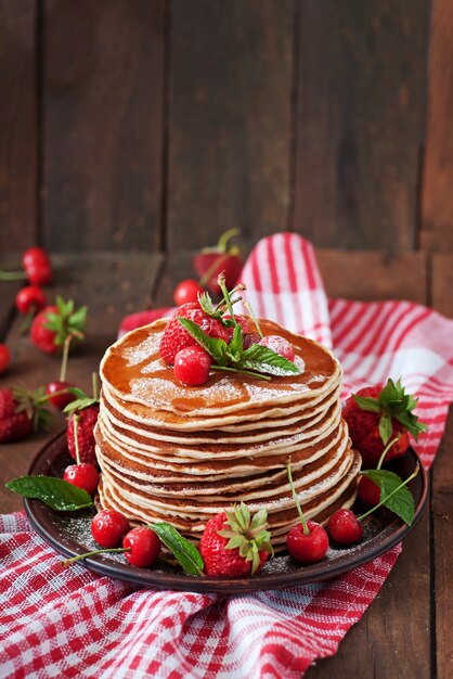 Pancakes with berries and syrup in a rustic style