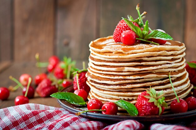 Pancakes with berries and syrup in a rustic style