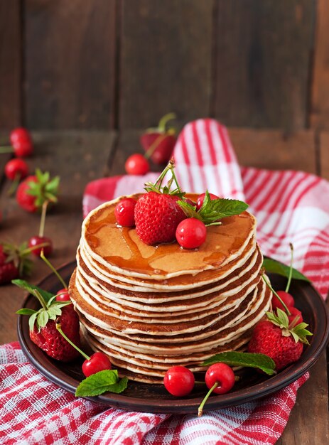 Pancakes with berries and syrup in a rustic style