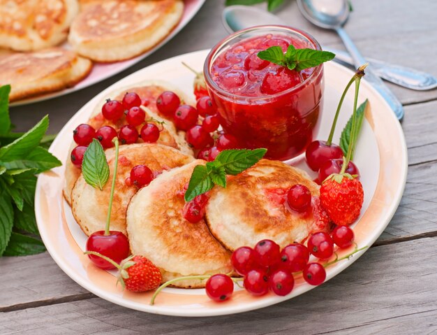 Pancakes with berries on a wooden table in a summer garden