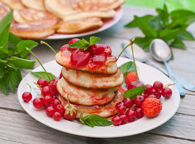 Pancakes with berries on a wooden table in a summer garden