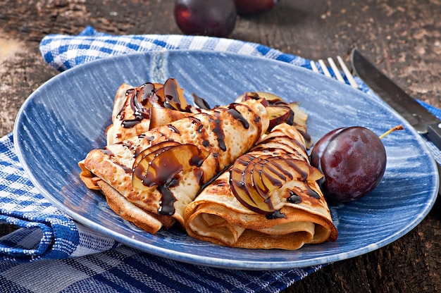 Pancakes with chocolate syrup and plums