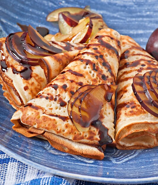 Pancakes with chocolate syrup and plums
