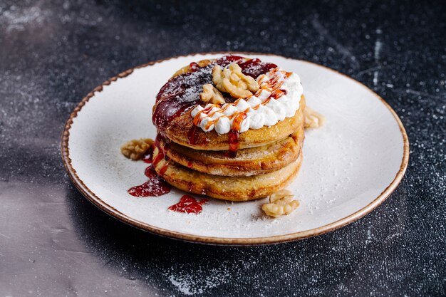 Pancakes with nuts, vanilla cream and strawberry sauce on the top.