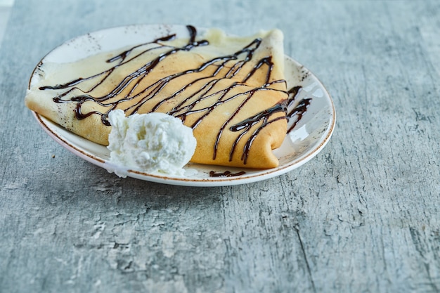 Foto gratuita frittelle con gelato alla vaniglia, cioccolato sul piatto bianco sulla superficie del marmo