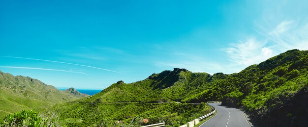 Panorama and beautiful view of mountains and blue sky with Asphalt road is meandering between blue fjord and moss mountains.