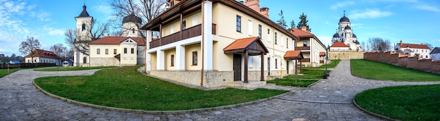 Panorama of the Capriana monastery. Visible Winter and Stone churches. Bare trees, green lawns and buildings, good weather in Moldova