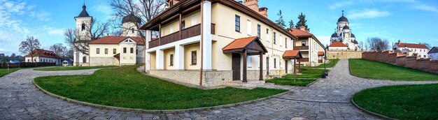 Panorama of the Capriana monastery. Visible Winter and Stone churches. Bare trees, green lawns and buildings, good weather in Moldova