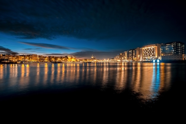 Panoramic shot of a night skyline with light reflections on the water