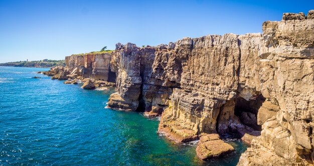Panoramic shot of the rocks beside the ocean in Cascais, Portugal