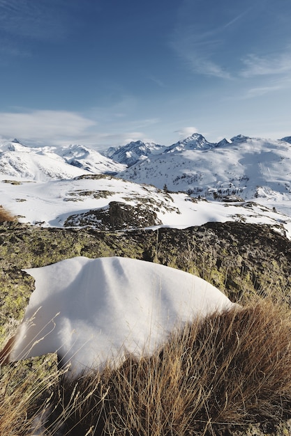 Panoramic shot of snow covered French alps with the sun shining under blue skies