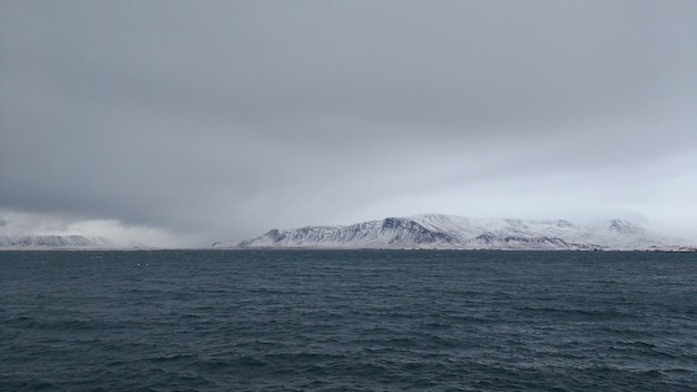 Panoramic shot of a snow covered mountain coast on a cloudy day