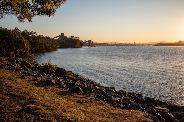 Panoramic shot of a stony shoreline with the sun in the horizon