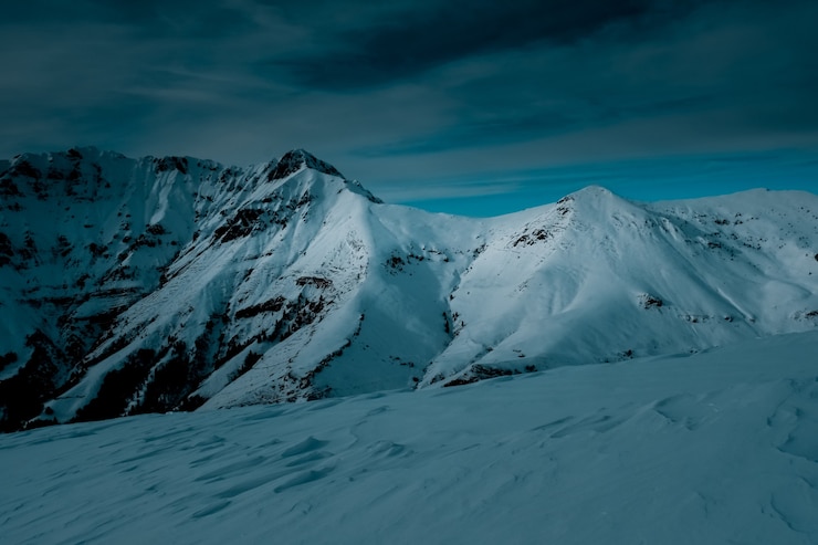 Free Photo panoramic shot on top of a snow covered mountain under cloudy skies