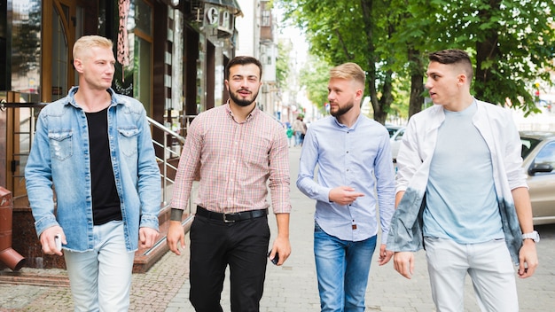 Panoramic view of male friends walking together on pavement