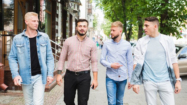 Панорамный вид друзей-мужчин, идущих вместе на тротуаре