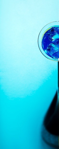 Panoramic view of martini glass with ice cubes on blue backdrop