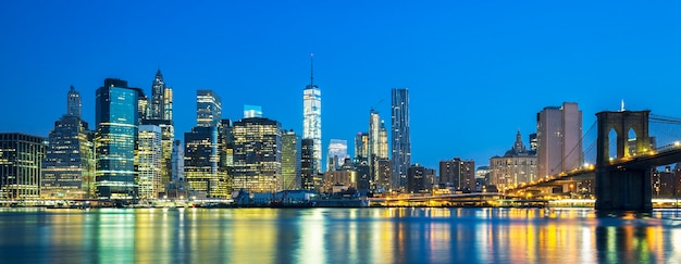 Panoramic view of New York City Manhattan midtown at dusk with skyscrapers illuminated over east river