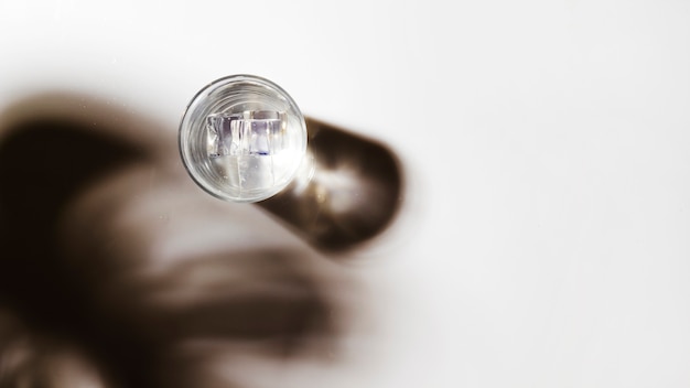 Panoramic view of water glass with ice cubes on white backdrop