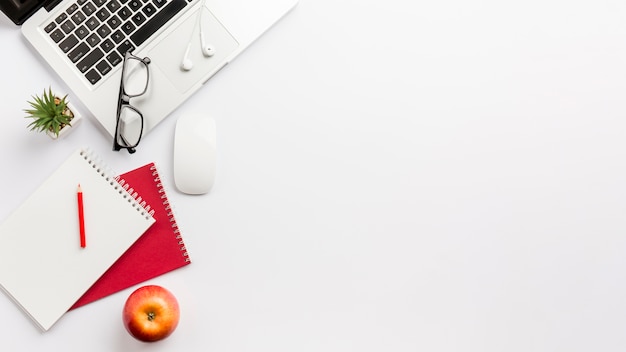 Panoramic view of white office desk with laptop,apple and stationeries