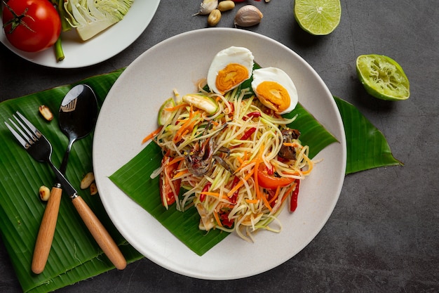 Papaya salad served with rice noodles and vegetable salad decorated with thai food ingredients.