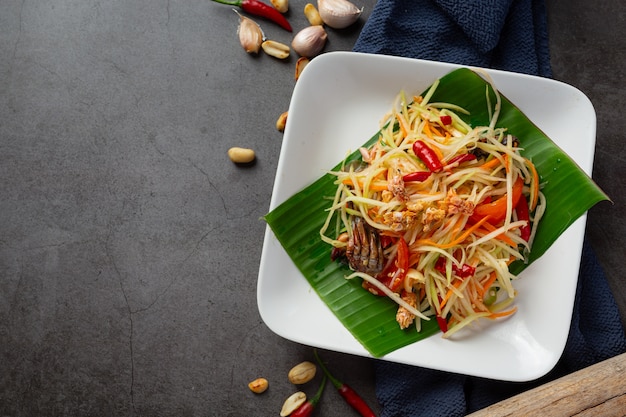 Салат из папайи, подается с рисовой лапшой и овощным салатом. Украшен ингредиентами тайской кухни.