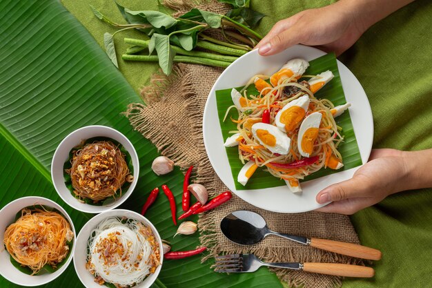 ライスヌードルと野菜のサラダを添えたパパイヤサラダタイの食材で飾られています。