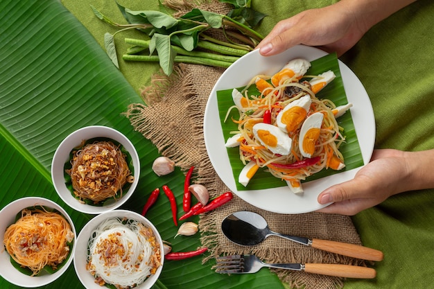 Papaya salad served with rice noodles and vegetable salad Decorated with Thai food ingredients.