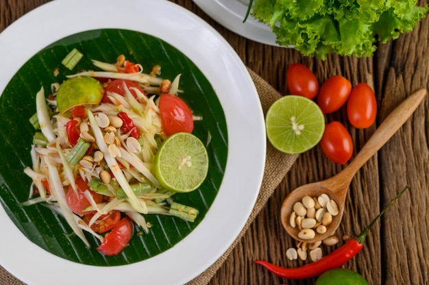 Papaya Salad (Som tum Thai) on a white plate on a wooden table.