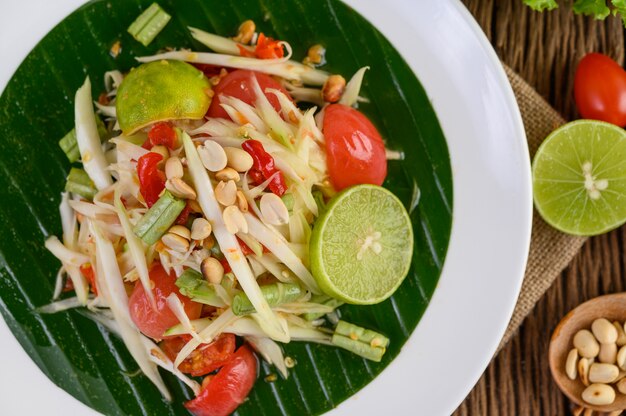 Papaya Salad (Som tum Thai) on a white plate on a wooden table.