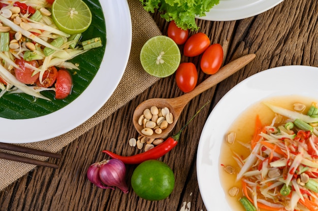 Papaya Salad (Som tum Thai) on a white plate on a wooden table.