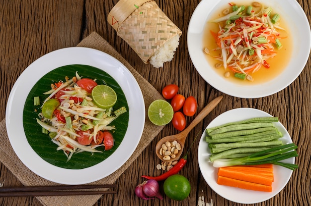 Papaya Salad (Som tum Thai) on a white plate on a wooden table.