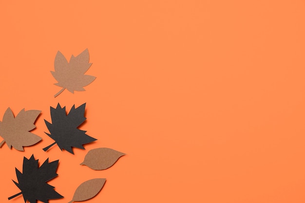 Paper autumn leaves on orange background with copy space