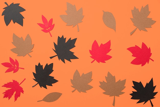 Free photo paper autumn leaves on orange background