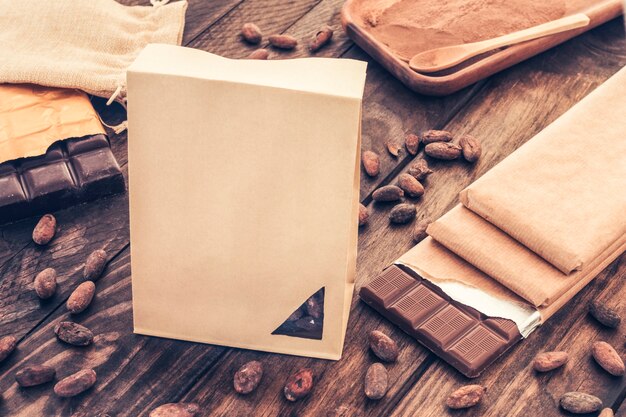 Paper bag with chocolate bars and cocoa beans on wooden table