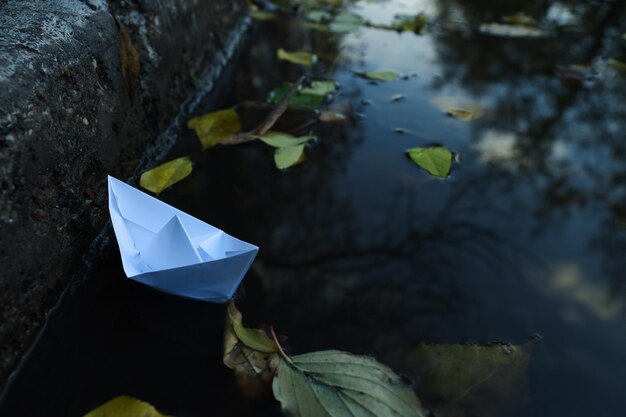 Paper boat in puddle outdoor in rainy weather