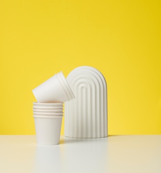Бумажные картонные белые чашки для кофе, желтый фон. экологичная посуда, без отходов