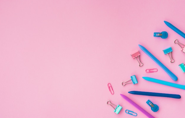 Paper clip and colorful crayon color at corner of the pink background
