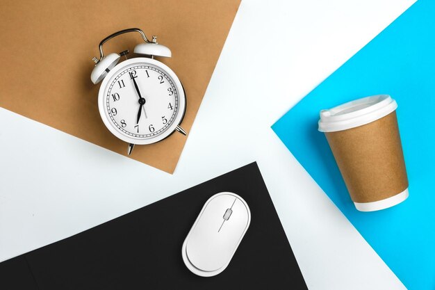 Paper cup computer mouse and alarm clock on colored paper background