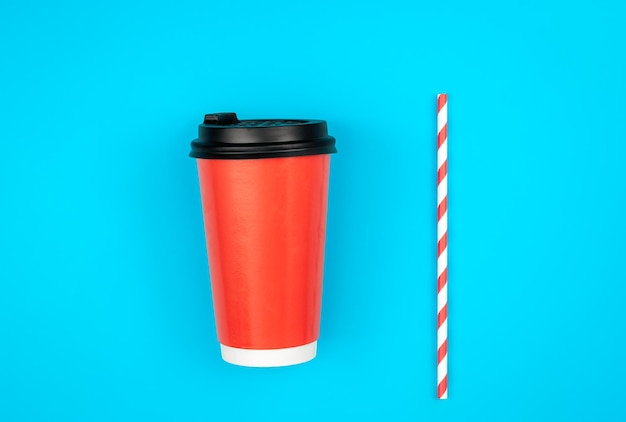 Paper cup and paper straw for drinks on a blue background flat lay