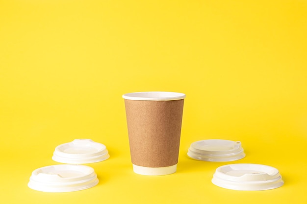 Free photo paper cup and plastic lids on a yellow background isolated