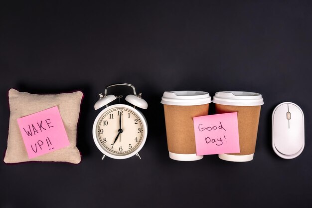 Paper cups alarm clock computer mouse and bright paper stickers top view